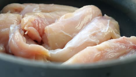 carne de pollo cruda en un plato sobre un fondo blanco