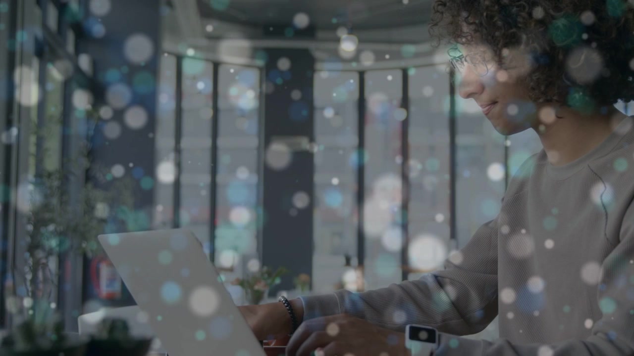 Man typing on laptop, lifting mug while drifting bokeh overlay obscuring screen for tech work