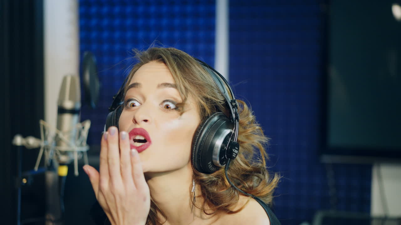 Vinnitsa, Ukraine - May 2019: Young woman recording a song in a professional studio