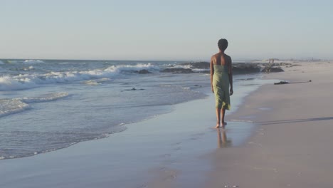 Video-of-african-american-woman-walking-on-beach-at-sunset