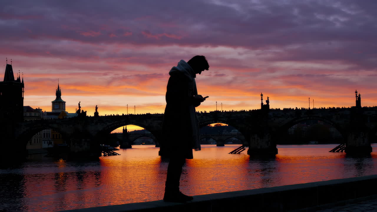 Man using phone at Charles Bridge sunset