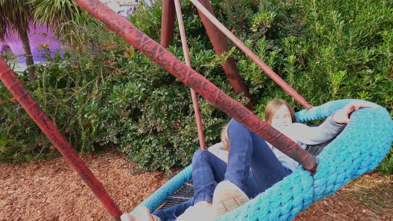 공원에서 큰 둥근 스에 타고 있는 두 소녀. 자연에서 어린이들을 위한 재미.