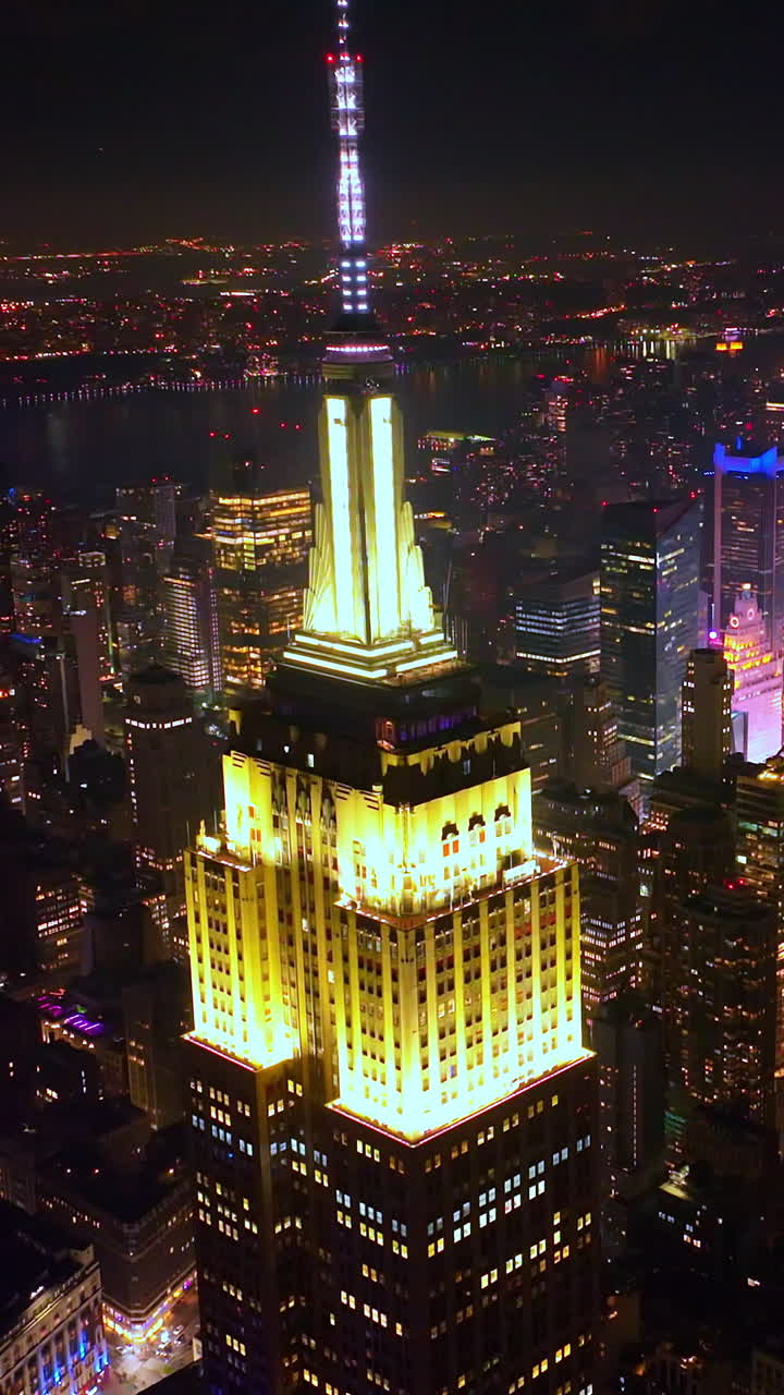 Fascinating Empire State building with lighted top at night. Striking scenery of New York skyscrapers at the backdrop of black skies. Vertical video