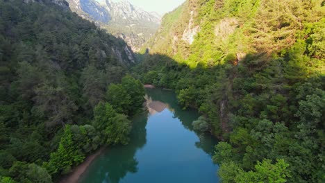vuelo de drones fpv sobre un hermoso río tranquilo rodeado de árboles y montañas - niños y personas descansando en una playa de arena en un arroyo en el líbano