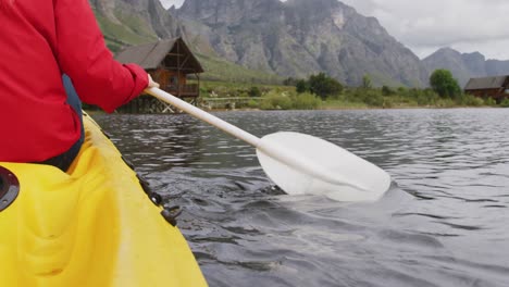 Caucasian-woman-having-a-good-time-on-a-trip-to-the-mountains,-kayaking-on-a-lake,-holding-a-paddle