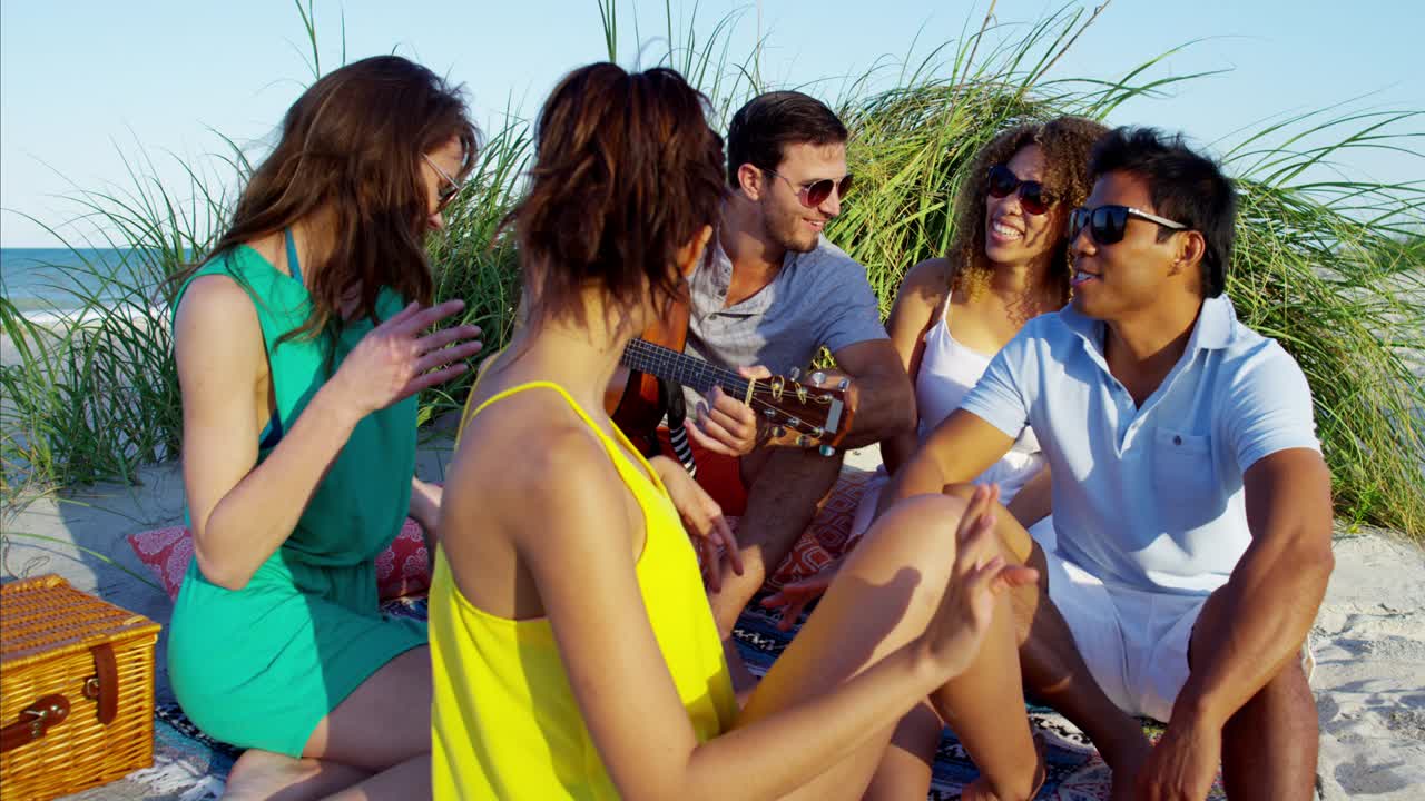 Giovani multietnici che fanno un picnic in spiaggia