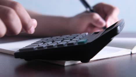 person calculating using calculator and notebook