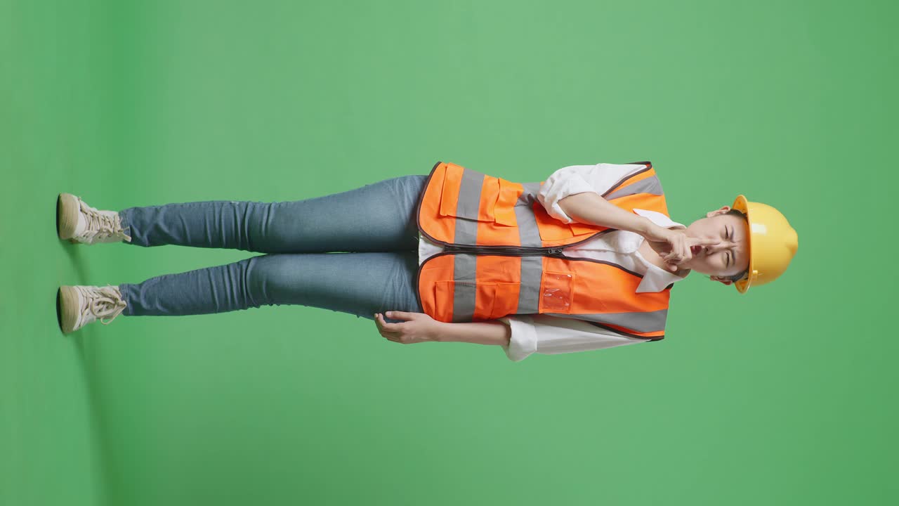 Full Body Of Asian Female Engineer With Safety Helmet Making Shh Gesture While Standing In The Green Screen Background Studio
