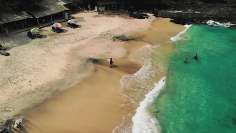 people enjoying the waves at a white sand beach in east bali