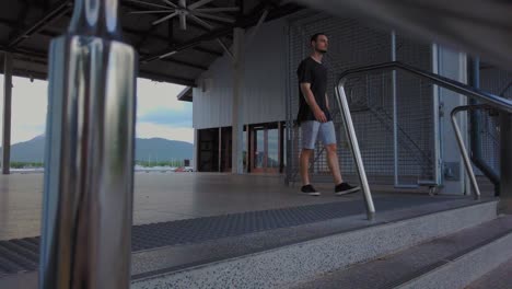 a young man wearing casual clothes going down in the staircase and looking around outside