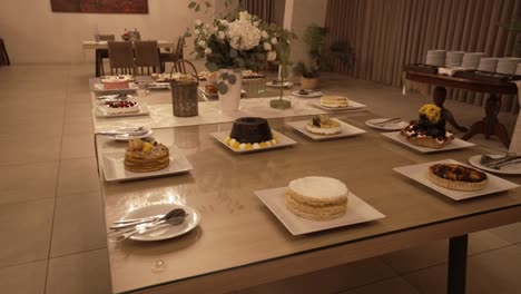assorted cakes and desserts arranged on a table in an elegantly decorated dining area