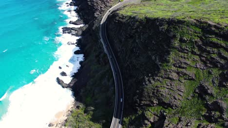 birds eye view of hawaiian highway with a tropical beach on one side and mountains on the other