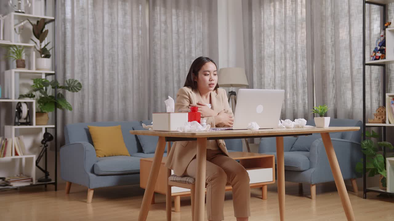 아픈 아시아 사업가 여성은 집에서 거실에서 노트북으로 일하는 동안 차가운