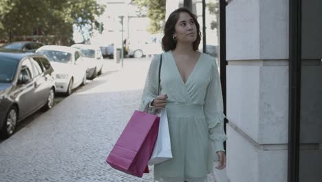 happy woman walking along street with shopping bags