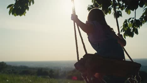 Rear-view-blonde-girl-swinging-high-in-summer-day.