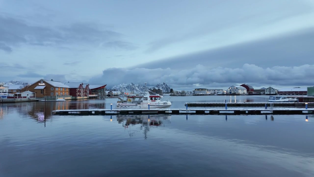 Norveç, Svolvær'de sakin liman manzarası, karlı dağlar, durgun su.