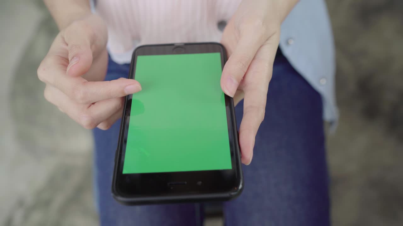 joven asiática alegre sentada en un café usando un dispositivo de teléfono inteligente con pantalla verde para hablar, leer y enviar mensajes de texto. concepto de estilo de vida de las mujeres.