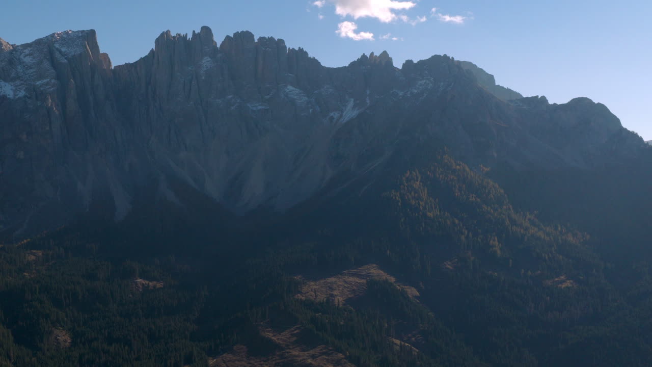 Pemandangan udara sinematik Dolomites di Italia, puncak alpine terjal yang bersinar saat fajar, tebing dramatis dan lembah berbayangan dalam menciptakan suasana ketinggian yang tenang