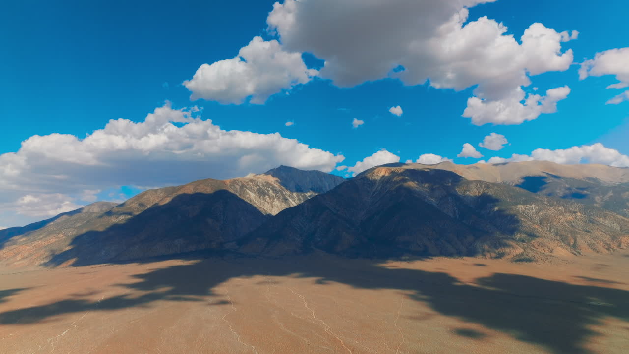 Stunning mountains in the shadows of white fluffy clouds. Nevada rocks at backdrop of azure skies with soft clouds.