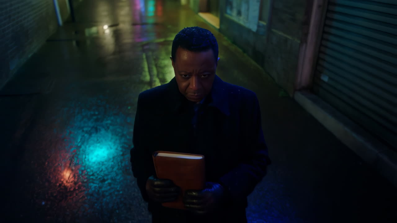 Man holding a book in a dark, neon-lit alley