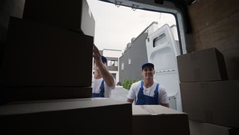 two young workers of removal company are loading boxes and furniture into a minibus