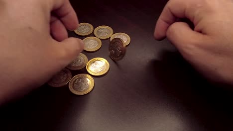 Moneda-De-10-Pesos-Girando-A-Mano-Sobre-Una-Mesa-De-Madera