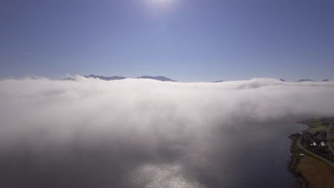 aerial of clouds drifting over a fjord