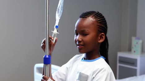 Portrait-of-sick-girl-holding-iv-drip-stand