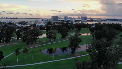 gentle fly over aerial shot of normandy shore golf course in florida with dusky skyline in background