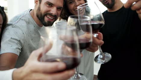 smiling friends clinking wineglasses in front of camera