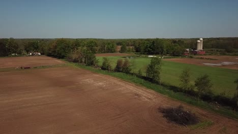 Flying-past-an-empty-field-with-barn-and-grain-silo-visible-in-background