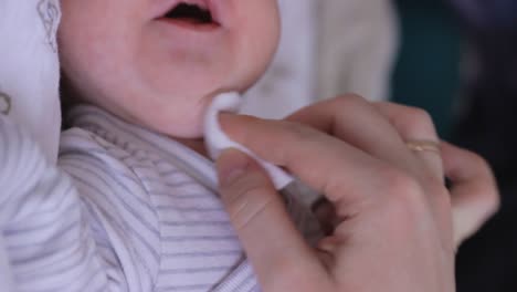 mother's hand cleaning crying newborn baby's mounth - close up