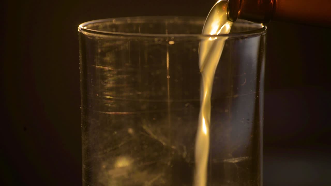 해질녘에 흐릿한 필스너 에일 맥주가 유리잔에 쏟아지고 있다