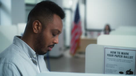 african american man thinks which presidential candidate to vote for close up of african american man thinking and choosing which presidential candidate to vote for in voting booth at polling station us citizen during national election day in united states of america