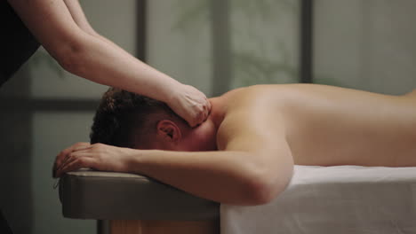 masaje relajante para curar el dolor de cuello y el dolor de cabeza masajista profesional está masajeando el cuerpo masculino