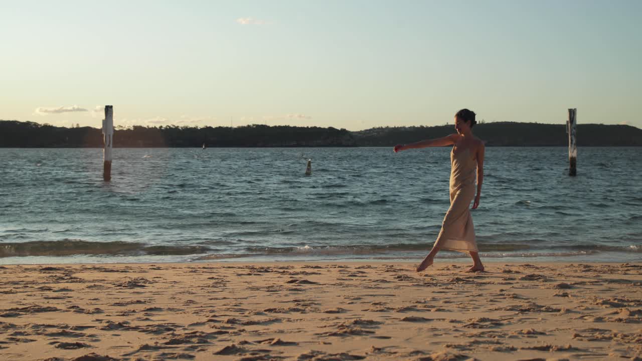 아름다운 일몰 동안 긴 드레스를 입고 해변을 따라 걷는 젊은 지중해 여성의 넓은 사진