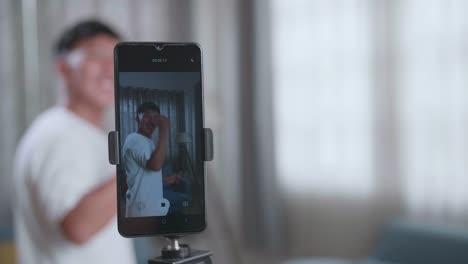 display smartphone of asian boy dancing while shooting video content for social networks