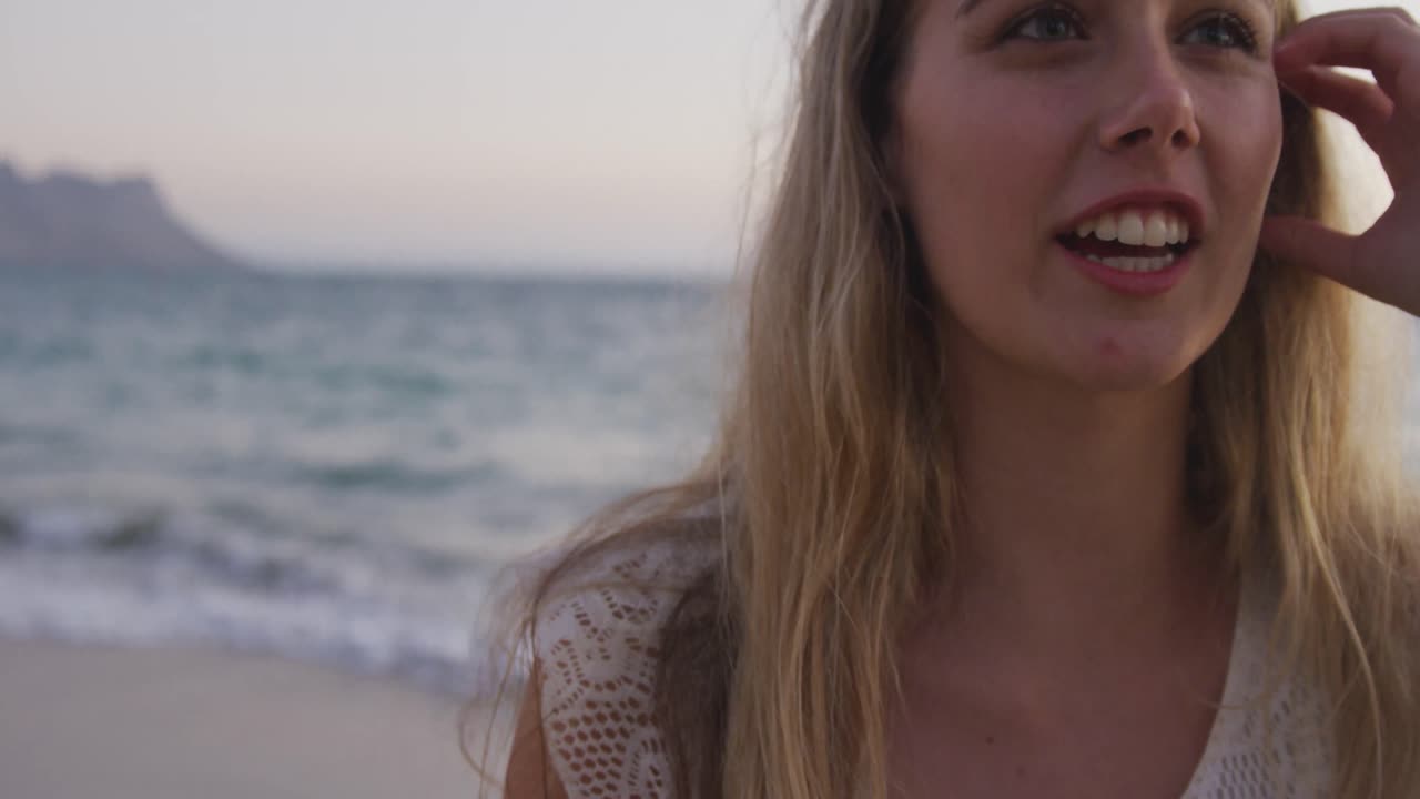 백인 여성이 바 ⁇ 가에서 시간을 즐기고 있습니다.