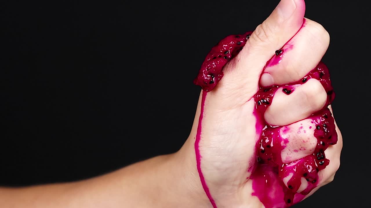 la mano apretando la fruta del dragón, el jugo goteando