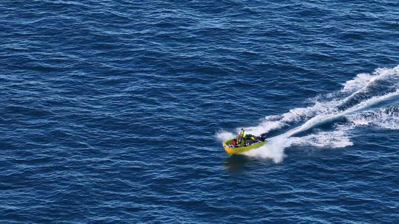 Rekaman udara sudut tinggi sebuah perahu motor kuning yang menciptakan jejak putih di Surfers Paradise.