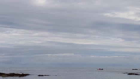 Kayakistas-Remando-Lentamente-Más-Allá-De-Las-Rocas-Marinas-Con-Nubes-Dramáticas-Lee-Bay-Devon-Uk-4k