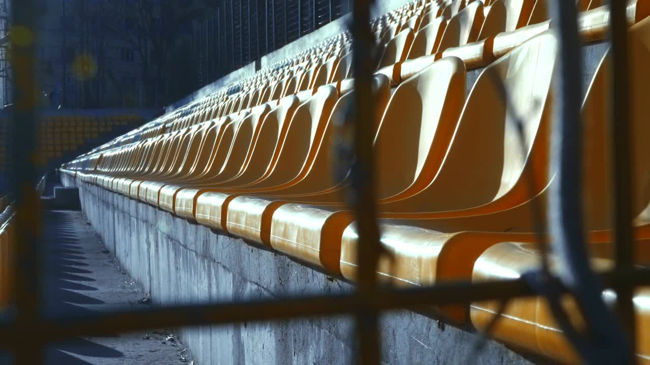 금속 울타리 뒤에 빈 경기장에서 노란색 의자, 4k