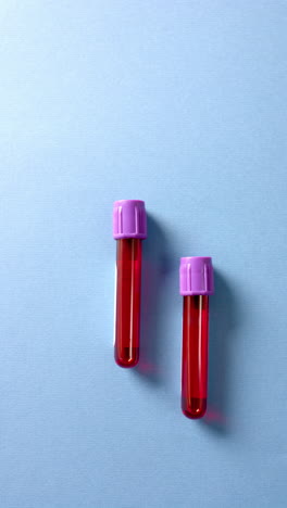 vertical video of blood samples on blue background with copy space, slow motion