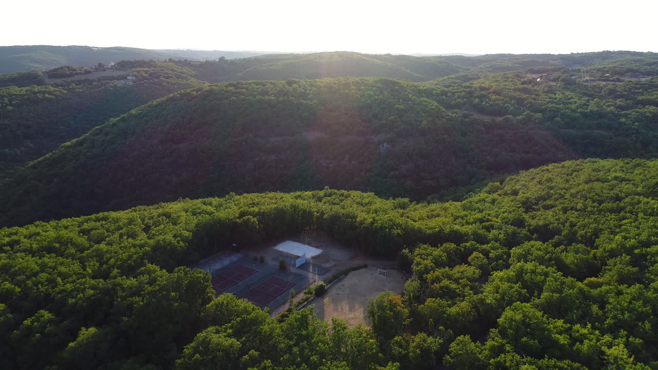 campo deportivo al aire libre en el medio de un bosque disparado por un dron aéreo. hora de la puesta del sol