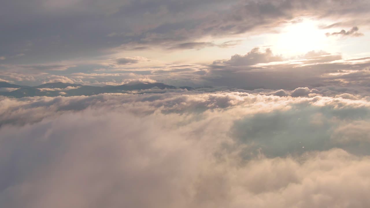 Magnifico volo sopra una distesa di nuvole stratocumuli e cumuli bianche, leggere e gonfie, con sole splendente nel cielo azzurro, avvicinamento aereo.