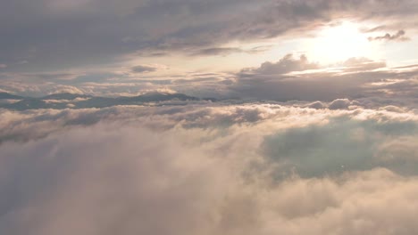 gorgeous flight above blanket of white wispy and puffy stratus and cumulus clouds with bright sun in blue sky, aerial approach