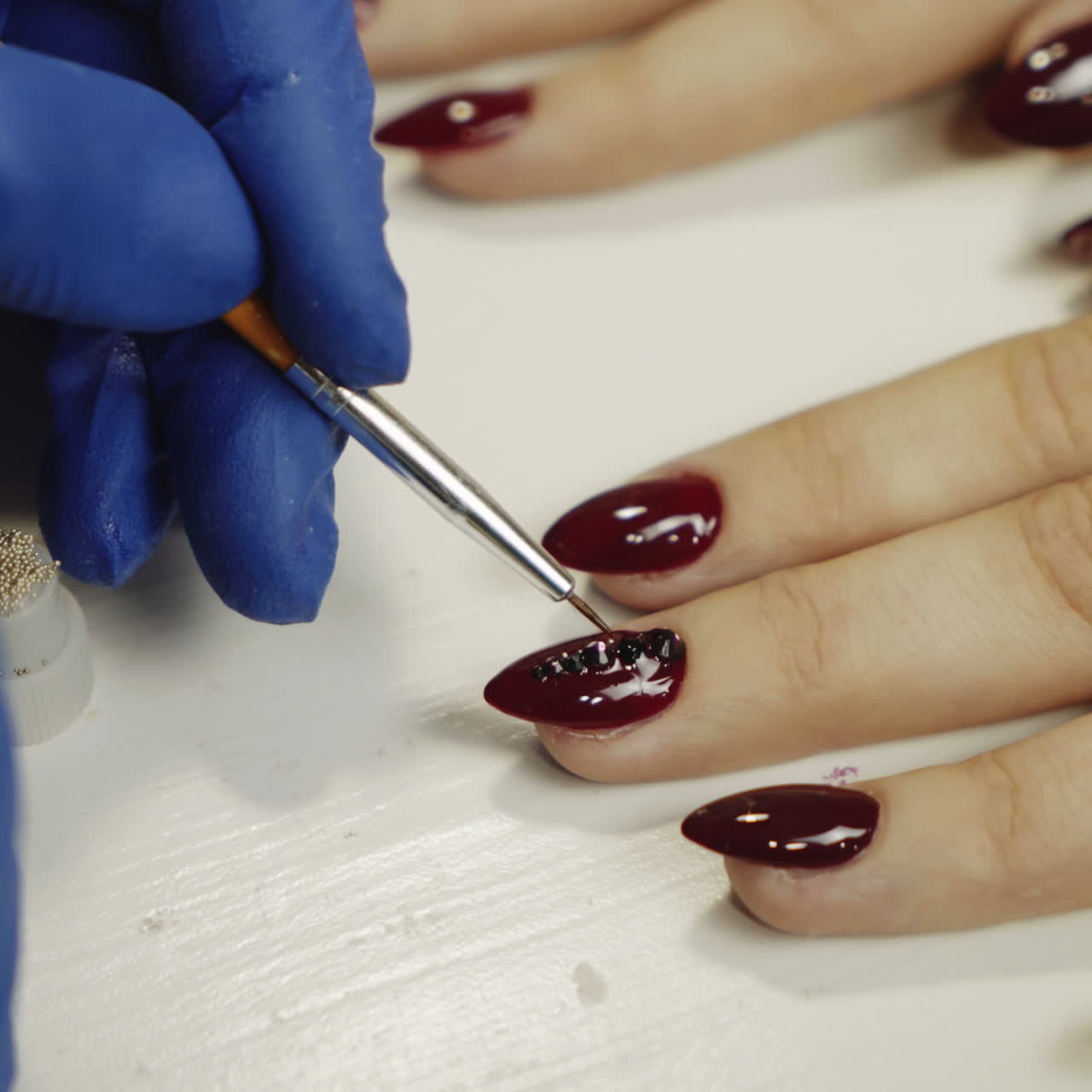 Manicurist attaching rhinestones on nails. Manicure in beauty salon. Square video