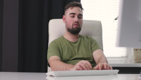 Hungry-Man-Eating-A-Rice-Cracker-While-Using-Desktop-Computer-At-Office