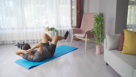 Male-doing-morning-gymnastics-and-fitness-exercises-on-mat-at-home-in-living-room.