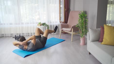 male doing morning gymnastics and fitness exercises on mat at home in living room.